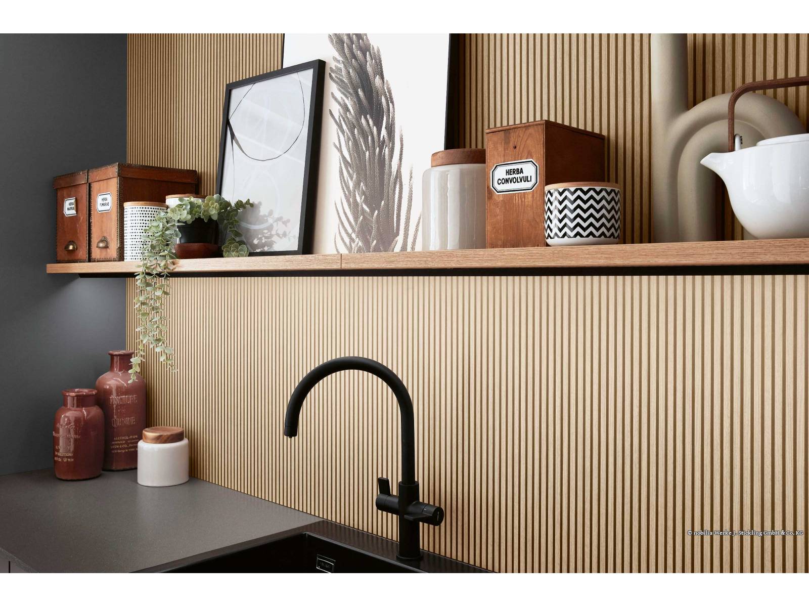 Die Küchenlinie «Savona» überzeugt durch die Kombination von ­schiefergrauen Fronten mit der Nischenverkleidung «Oak Line nature» und wirkt im Zusammen­spiel mit der schwarzmatten Armatur, der Abdeckung und dem Becken elegant. DIPL. ING. FUST.