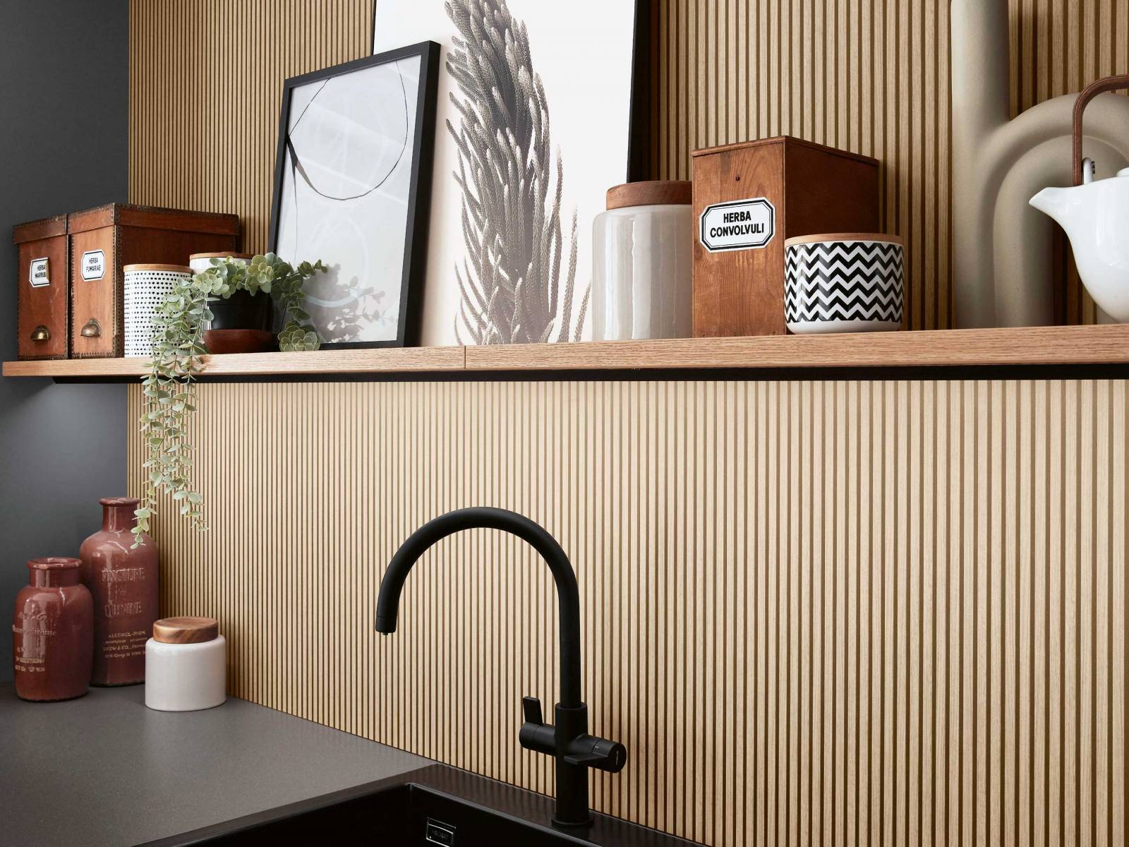 Die Küchenlinie «Savona» überzeugt durch die Kombination von ­schiefergrauen Fronten mit der Nischenverkleidung «Oak Line nature» und wirkt im Zusammen­spiel mit der schwarzmatten Armatur, der Abdeckung und dem Becken elegant. DIPL. ING. FUST.