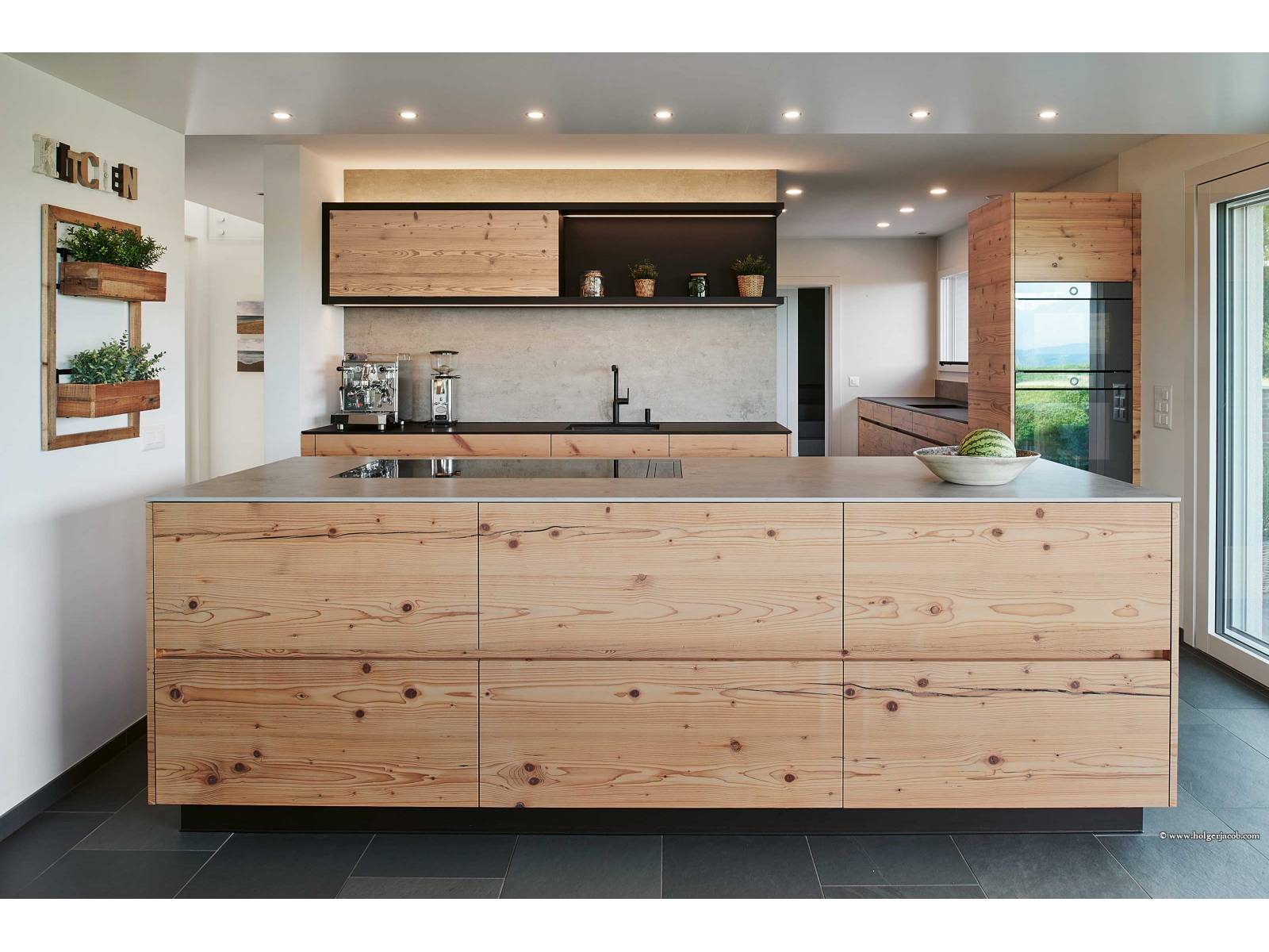 Eine Küche mit Charakter ist bei diesem Umbauprojekt entstanden, was nicht zuletzt auf die Materialwahl zurückzuführen ist. Denn für die Fronten wurde hier Altholz aus Fichte gewählt, das sich die Bauherrschaft vor Ort beim Küchenbauer ausgesucht hat, kombiniert mit einer Hochschrankzeile in Schwarz und einer Abdeckung in Betonoptik. BRUNNER KÜCHEN.