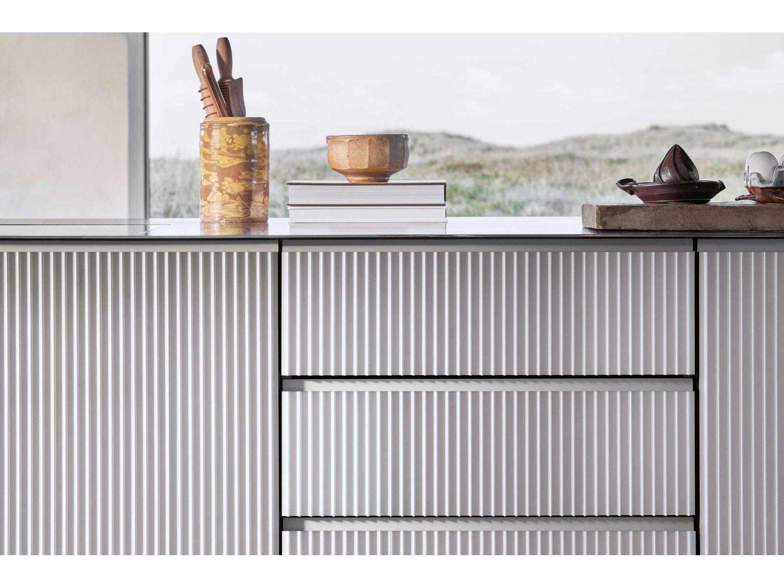 Das dänische Unternehmen überrascht mit seiner neusten Küche: «V3» orientiert sich in ihrem Aufbau an der bereits bestehenden Küche «V1», die frei­stehenden Module sind aber in natürlich eloxiertes Aluminium gehüllt – mit vertikal stranggepressten Profilen, die sich elegant um die Kanten wölben. VIPP.