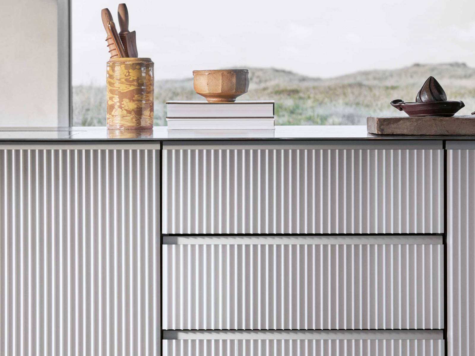 Das dänische Unternehmen überrascht mit seiner neusten Küche: «V3» orientiert sich in ihrem Aufbau an der bereits bestehenden Küche «V1», die frei­stehenden Module sind aber in natürlich eloxiertes Aluminium gehüllt – mit vertikal stranggepressten Profilen, die sich elegant um die Kanten wölben. VIPP.