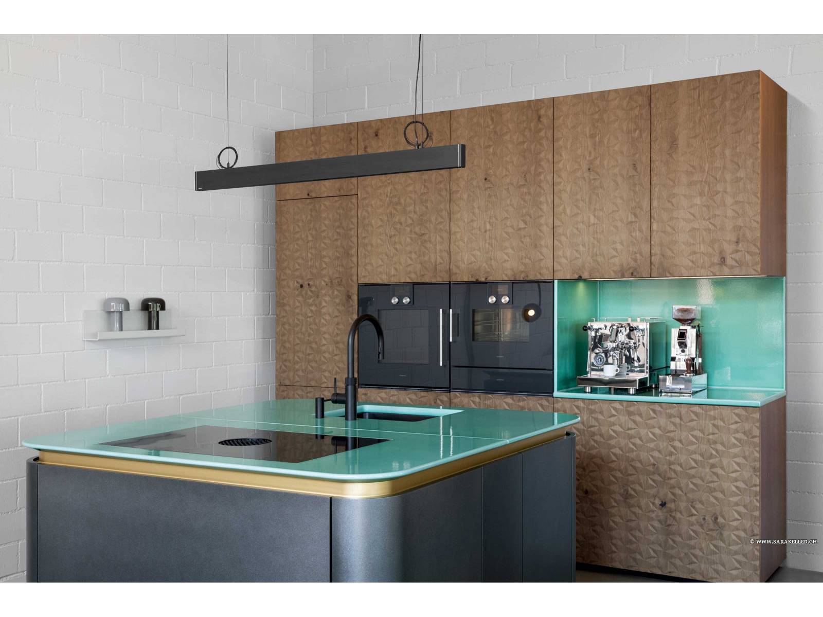 Eine einzigartige Kombination aus Reliefholz, lackiertem MDF, einer Lavastein-Abdeckung sowie goldenen Griff­mulden verdient in diesem Beispiel das Prädikat «extra­vagant». Gefertigt wurde die Küche in der Manufaktur des Unternehmens und mit Geräten von Gaggenau und Quooker kombiniert. ELBAU.