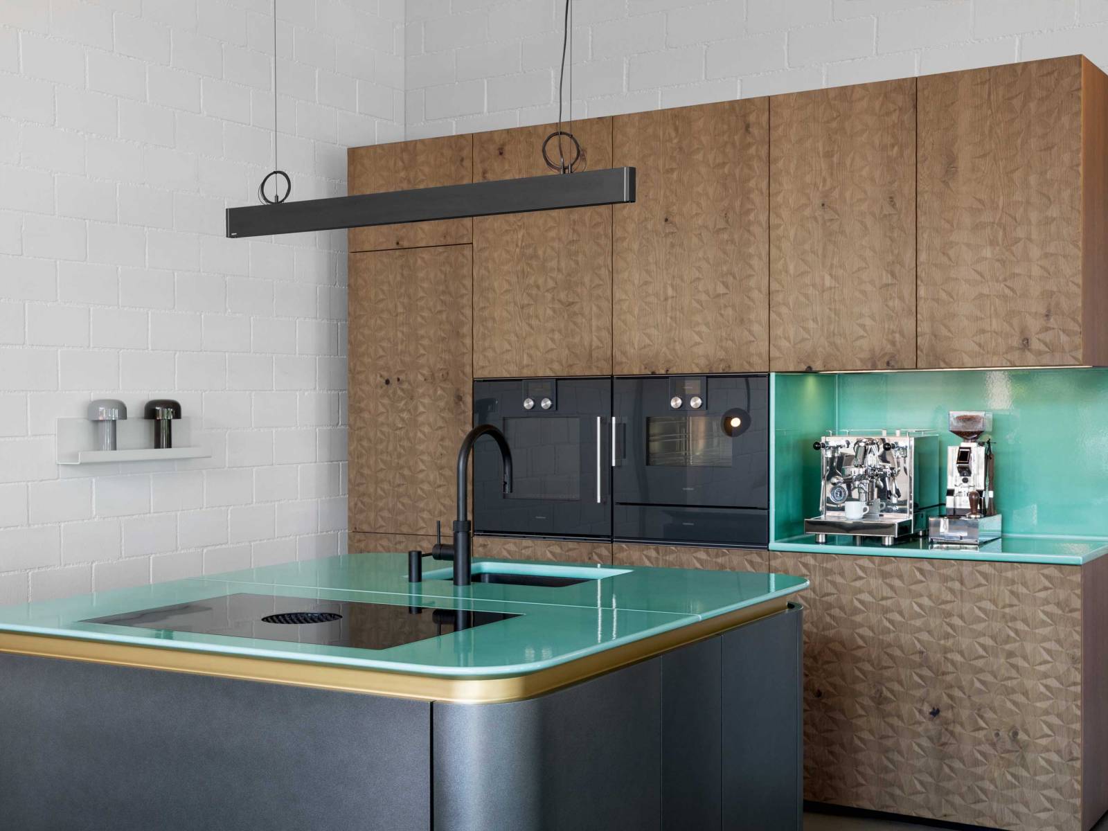 Eine einzigartige Kombination aus Reliefholz, lackiertem MDF, einer Lavastein-Abdeckung sowie goldenen Griff­mulden verdient in diesem Beispiel das Prädikat «extra­vagant». Gefertigt wurde die Küche in der Manufaktur des Unternehmens und mit Geräten von Gaggenau und Quooker kombiniert. ELBAU.