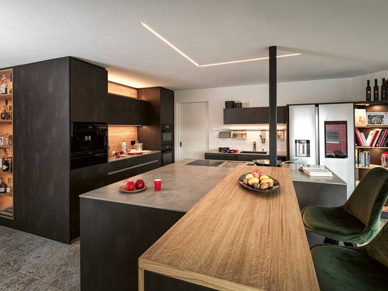 Die Küchenherstellerin vereint in diesem Beispiel Rohstahl mit Eiche und setzt mit pointierten Lichtquellen Akzente im Raum. Die asymmetrische Kücheninsel wirkt gleichzeitig raumbildend wie grosszügig. VERISET.