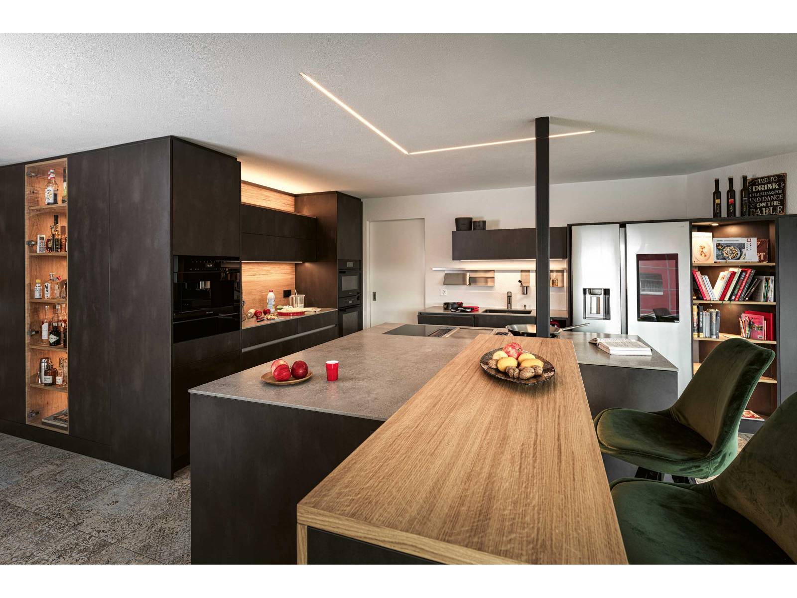 Die Küchenherstellerin vereint in diesem Beispiel Rohstahl mit Eiche und setzt mit pointierten Lichtquellen Akzente im Raum. Die asymmetrische Kücheninsel wirkt gleichzeitig raumbildend wie grosszügig. VERISET.