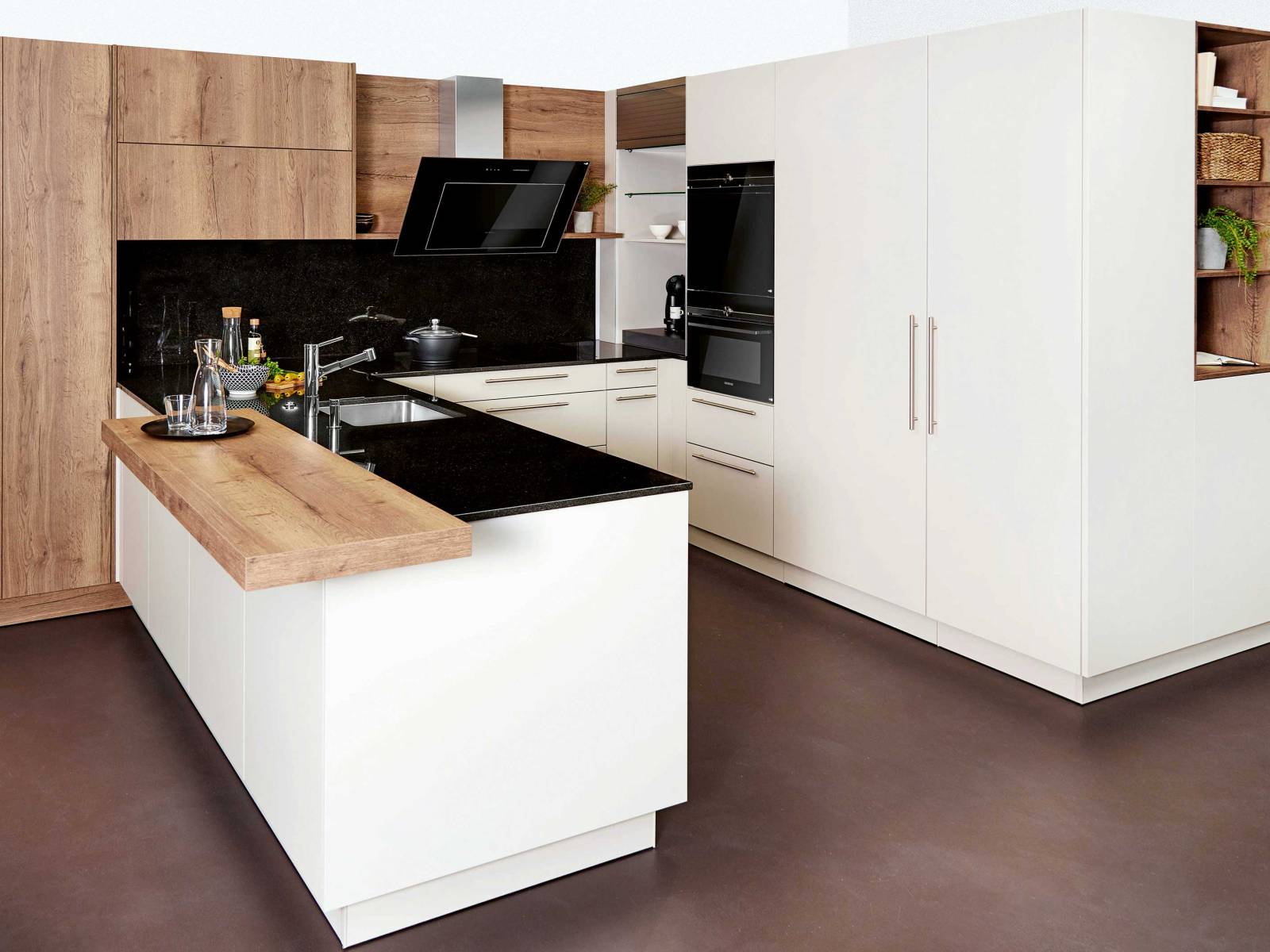 Holz, Granit und schlichtes Weiss lassen diese Küche modern und wohnlich daherkommen. Ein technisches Highlight ist die Dunstabzugshaube, deren Leistung sich nicht nur am Kochdunst anpasst, sondern bei Bedarf auch bequem per Handy oder Tablet gesteuert werden kann. SABAG.