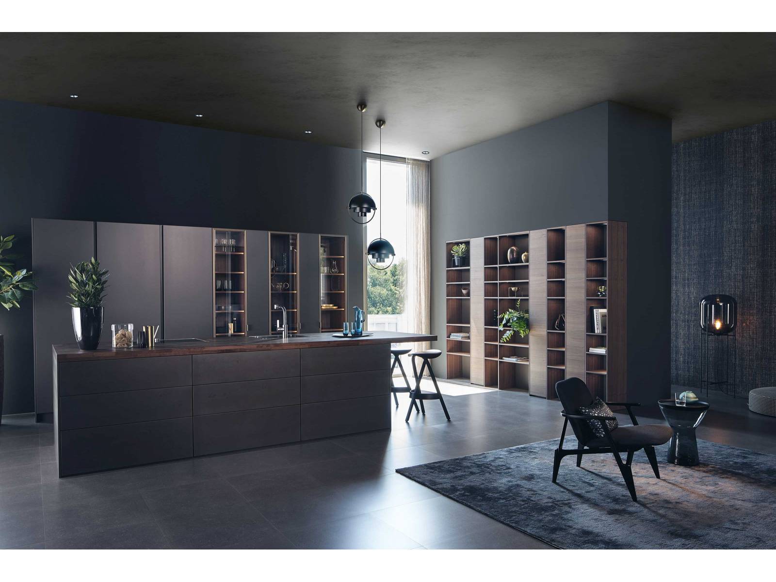 Das Küchensortiment des Unternehmens umfasst unter anderem Linien der Marke Leicht. Dieses Beispiel hier zeigt eine Version mit metallbeschichteten Oberflächen, Echtholzfronten und Glasvitrinen. DIPL. ING. FUST.