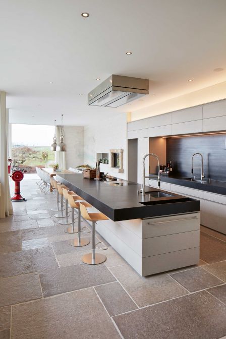 Der langgezogene Küchenblock mit Sitzgelegenheiten sowie die offene, LED-beleuchtete Nische mit Spülcenter erfüllen gleichzeitig die hohen Ansprüche an Funktion und Design. Die Nische ist mit Schwarzstahl ausgekleidet. BRUNNER KÜCHEN.