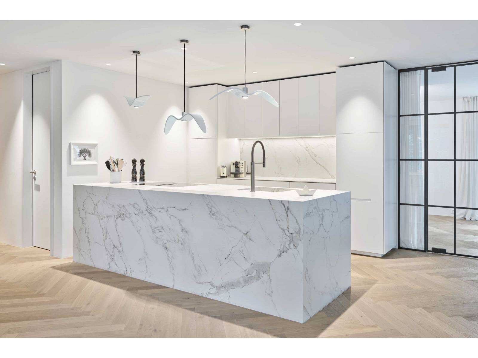 So wenig Küche wie möglich bei maximaler Wirkung: Alle Geräte sind hinter den reinweissen Fronten verborgen und stören den skulpturalen Charakter nicht. Der Inselblock ist ganz und gar in Dekton mit Marmoroptik gekleidet, was dem offenen Raum viel Eleganz verleiht und zum Industrial Look der Wohnung passt. STUBER TEAM.