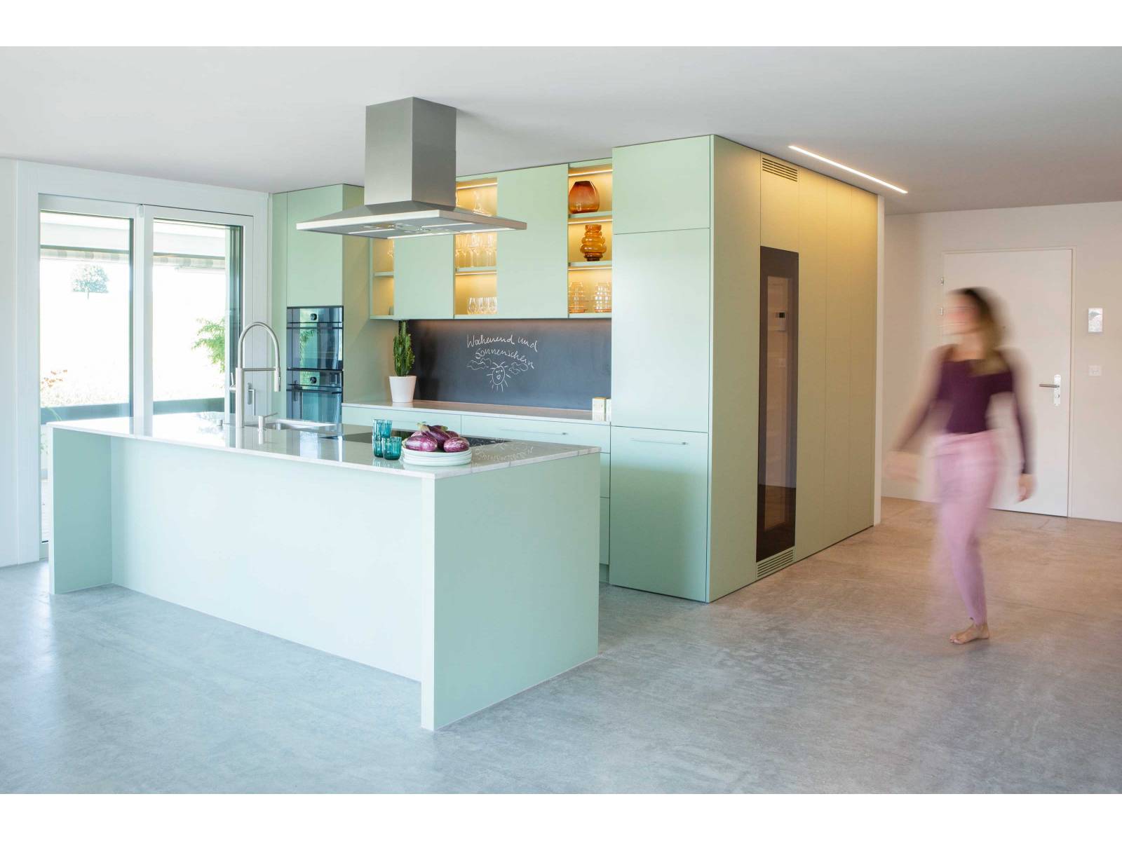Diese auf Mass geplante Küche sorgt in Pistaziengrün für einen frischen Start in den Tag. Die Oberschränke spielen mit offenen und geschlossenen Elementen, was neben dem zarten Farbton zusätzlich für Leichtigkeit sorgt. Die dimmbare LED-Beleuchtung setzt schönes Geschirr gekonnt in Szene und sorgt für viel Atmosphäre. ELBAU.