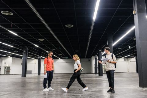 Das junge spanische Designteam um die Gründer Alberto Sánchez und Eduardo Villalón (links und rechts im Bild, zusammen mit ihrer Mitarbeiterin Pola Knabe) besichtigen die Kölner Messehalle 3.1, in der vom 13. bis 19. Januar 2020 ihre Version des Designs-Events «Das Haus» entstehen wird. Foto: koelnmesse, Roland Breitschuh.