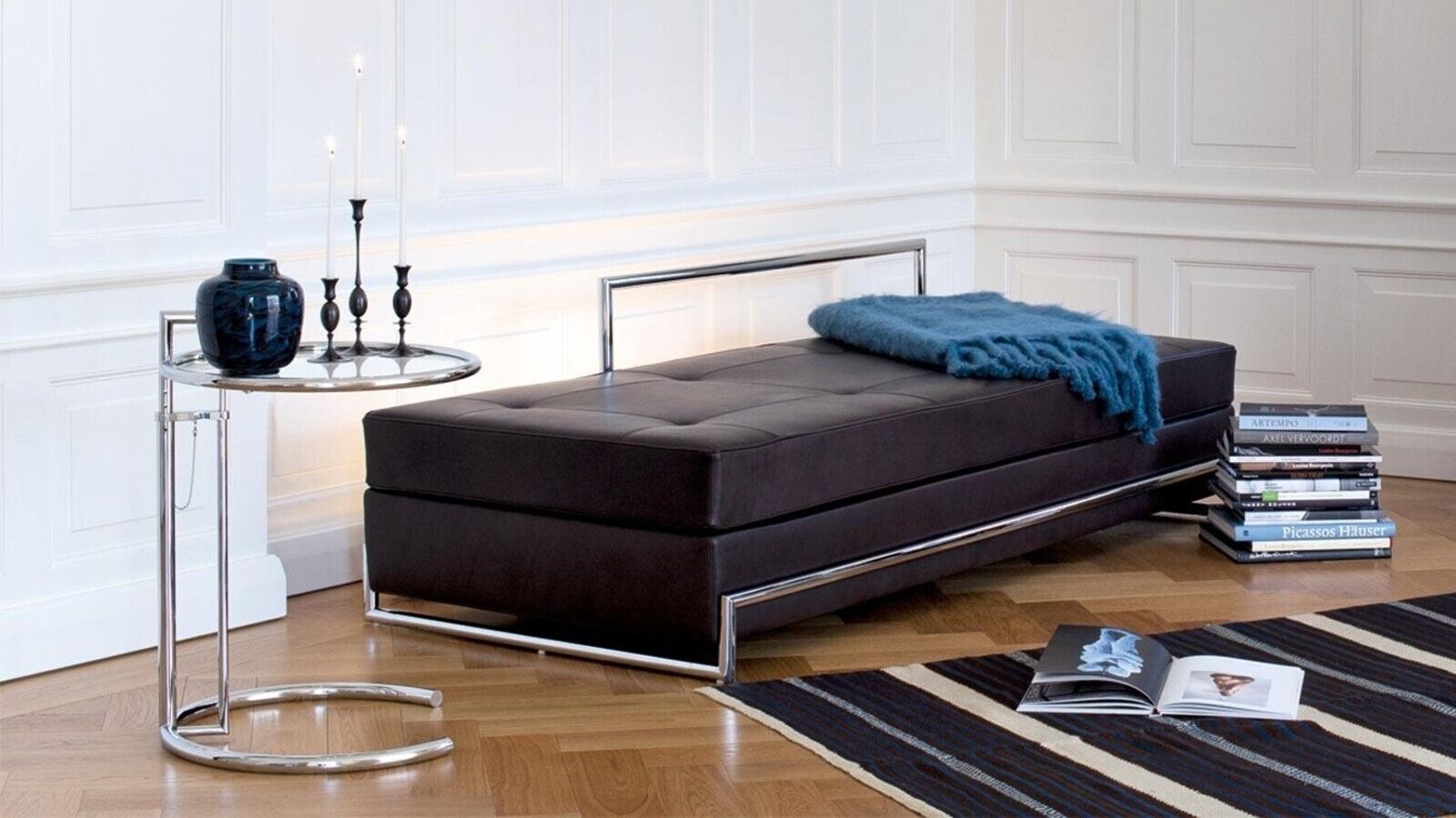 Der Adjustable Table E 1027, stilvoll dekoriert mit einer eleganten Vase und leuchtenden Kerzen, verleiht dem Raum eine zeitlose Ästhetik. Foto: © Classicon / Ambientedirect