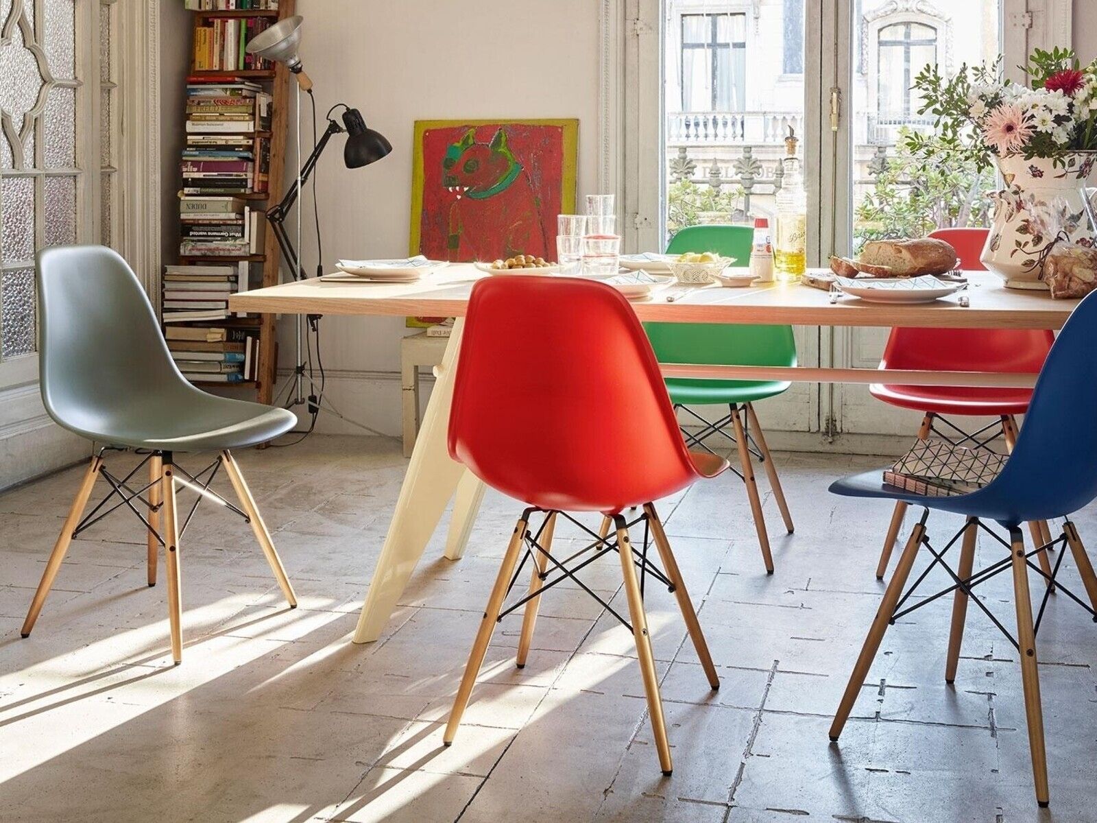 Eames-Stühle in verschiedenen Farben harmonieren wunderbar mit einem Holztisch. Foto: © Vitra / Ambientedirect
