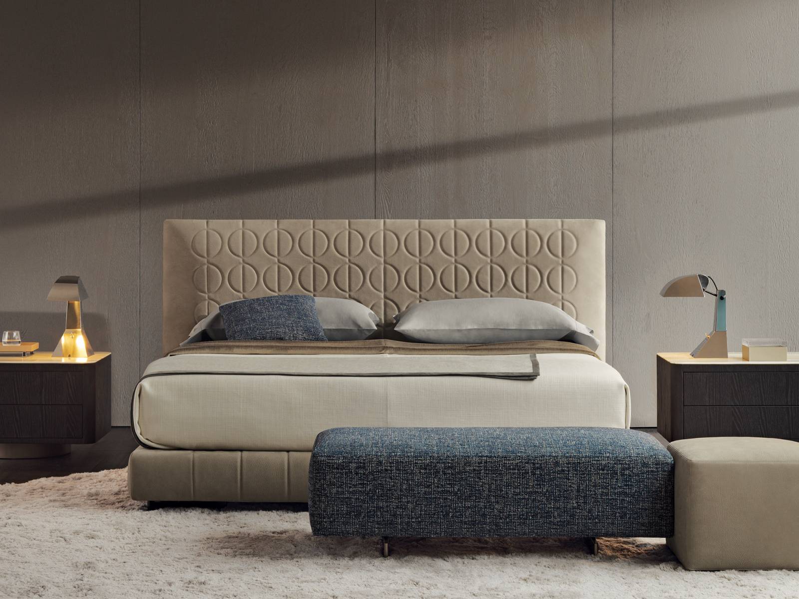 Steppmuster mal anders: Hier zieren Kreise, die von einer vertikalen Linie durchlaufen werden, das exklusive und hohe Kopfteil von Bett «Curtis». Die Linien werden im Bettgestell wieder aufgenommen. Den Bezug gibt es in Stoff oder Leder. Design: Rodolfo Dordoni. Minotti.