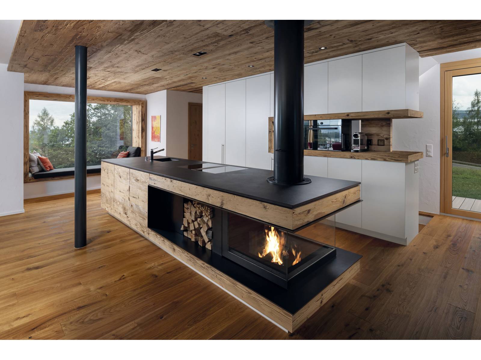 Das Unternehmen plant, entwickelt und stellt seit Jahren individuell gefertigte Feuerstellen her, die mit viel Liebe zum Detail in einheimischen Werkstätten gefertigt werden. In diesem Beispiel hier wurde die Feuerstelle in der Kücheninsel integriert und ist so konzipiert, dass trotzdem in der Küche möglichst wenig Hitze entsteht, dafür aber eine wohlige Atmosphäre geschaffen wird. Wirth &amp; Schmid.
