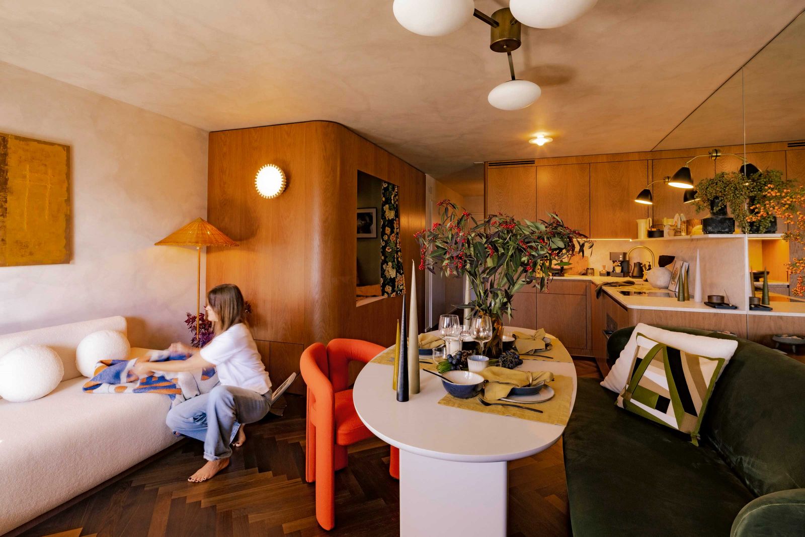 Der Blick in den Raum zeigt die geschickte Raumnutzung mit Küche, Essplatz, Koje und Sofabereich. Heimtextilien, Leuchten und Accessoires orientieren sich farblich an der Natur am und um den Crestasee.