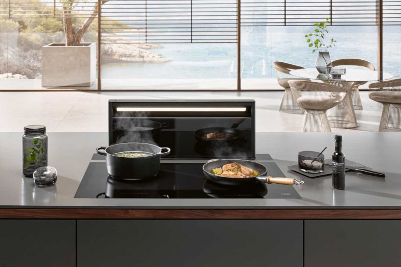 Verborgen: Im Unterschrank verborgen wartet sie auf ihren Einsatz: Die neue Downdraft-Haube «Black Levantar» fährt erst dann aus dem Induktionskochfeld heraus, wenn gekocht wird. Im ausgeschaltetem Zustand ist sie lediglich als schwarzer Glasstreifen sichtbar, der perfekt zur schwarzen Glaskeramik des Kochfeldes passt. Die Saugleistung passt sich automatisch dem Kochgeschehen an. MIELE.CH