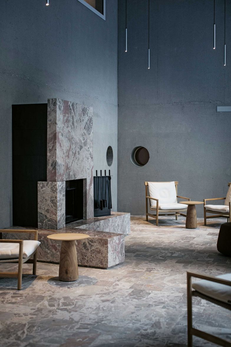 Das lichtdurchflutete Atrium ist ein hoher Raum mit offenem Feuer, in welchem gemütliche Sitzgelegenheiten zum Ausruhen einladen. Der rosa schimmernde Marmor stammt aus dem Tessiner Steinbruch in Arzo.