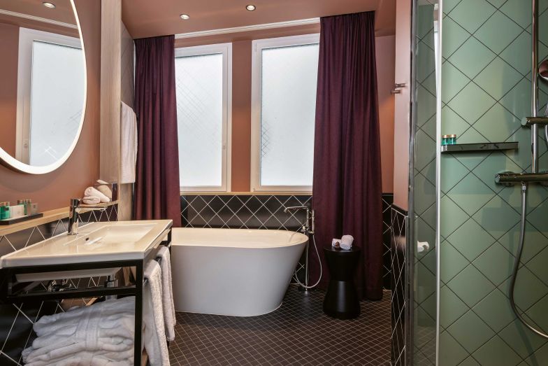 Daher stammt auch die Idee, die Fliesen in den Bädern diagonal zu verlegen, Verglasungen mit diagonalen Karos zu bedrucken und die Lehnen der Sitznischen in den Zimmern mit diagonalen Mustern zu besticken.