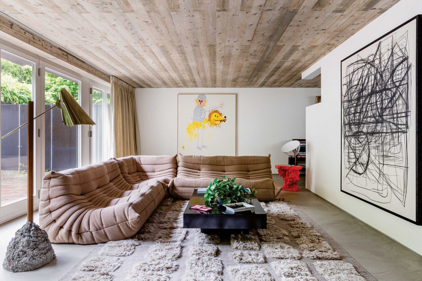 Im Wohnzimmer steht ein von Michel Ducaroy entworfenes Sofa neben einem roten Ständer von Sara Regal Alonso. Auf dem Ständer steht eine Taccia-Lampe aus den 1960er Jahren von Pier Giacomo Castiglioni und Achille Castiglioni. Die Kunst an der Wand: Löben Reiter Yeah, 2019, Andi Fischer/Sies + Höke, Düsseldorf. Peppi Bottrop/Sies + Höke, Düsseldorf Fotos: Belen Imaz, Copyright: Victoria-Maria Geyer.