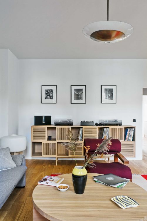 Der Designer Jacek Kolasinski entwarf den edlen Schallplattenschrank aus massivem Eichenholz mit quadratischen und platzsparenden Schiebeelementen im Wohnbereich. Dort verwahrt der Eigentümer seine Vinyl-Raritäten. Die Rundung des Sofatisches wiederholt sich in der Deckenleuchte aus Messing und Glas.