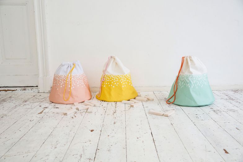 Wenn sich Teddybär und Püppchen Gute Nacht sagen, ist es an der Zeit, auch noch Bauklötze, Kuscheltiere und Spielzeugautos wegzuräumen. In der Spielzeugtasche der Tippkids-Kollektion verschwindet alles schnell und unkompliziert. Die hübschen Säcke, die an kleine Berge erinnern, stören selbst im Wohnzimmer nicht und können am nächsten Tag wieder ins Spiel integriert werden. Julica Design.