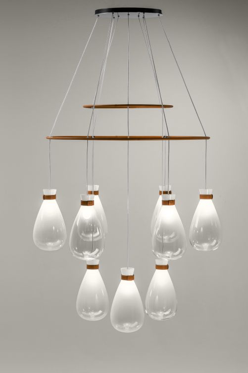 «Soffi» ist ein moderner Kronleuchter aus der gleichnamigen Familie, die vom Designer–Paar Gam Fratesi entwickelt wurde. Neun hängende Leuchtkörper aus venezianischem Glas reihen sich auf zwei Metallringen auf, jeweils schlicht umwickelt von einem schmalen Lederband, das das Glas zu halten scheint. Poltrona Frau.