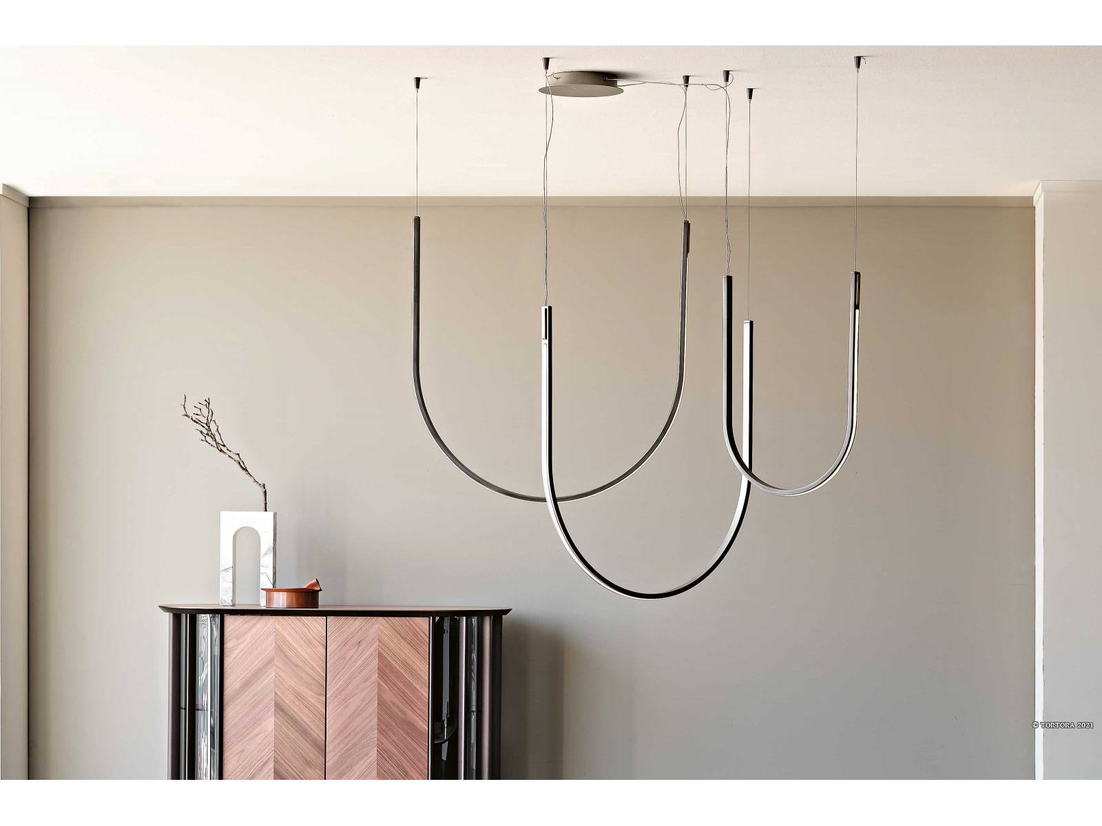 «Nahun» ist eine Komposition von Hängeleuchten, die es in zwei verschieden grossen Bögen gibt. Je nach Kombination und Anzahl der Bögen ergibt sich eine neue geometrische Form. Aus Stahl und Messing. Design: Studio Kronos. CATTELAN ITALIA.