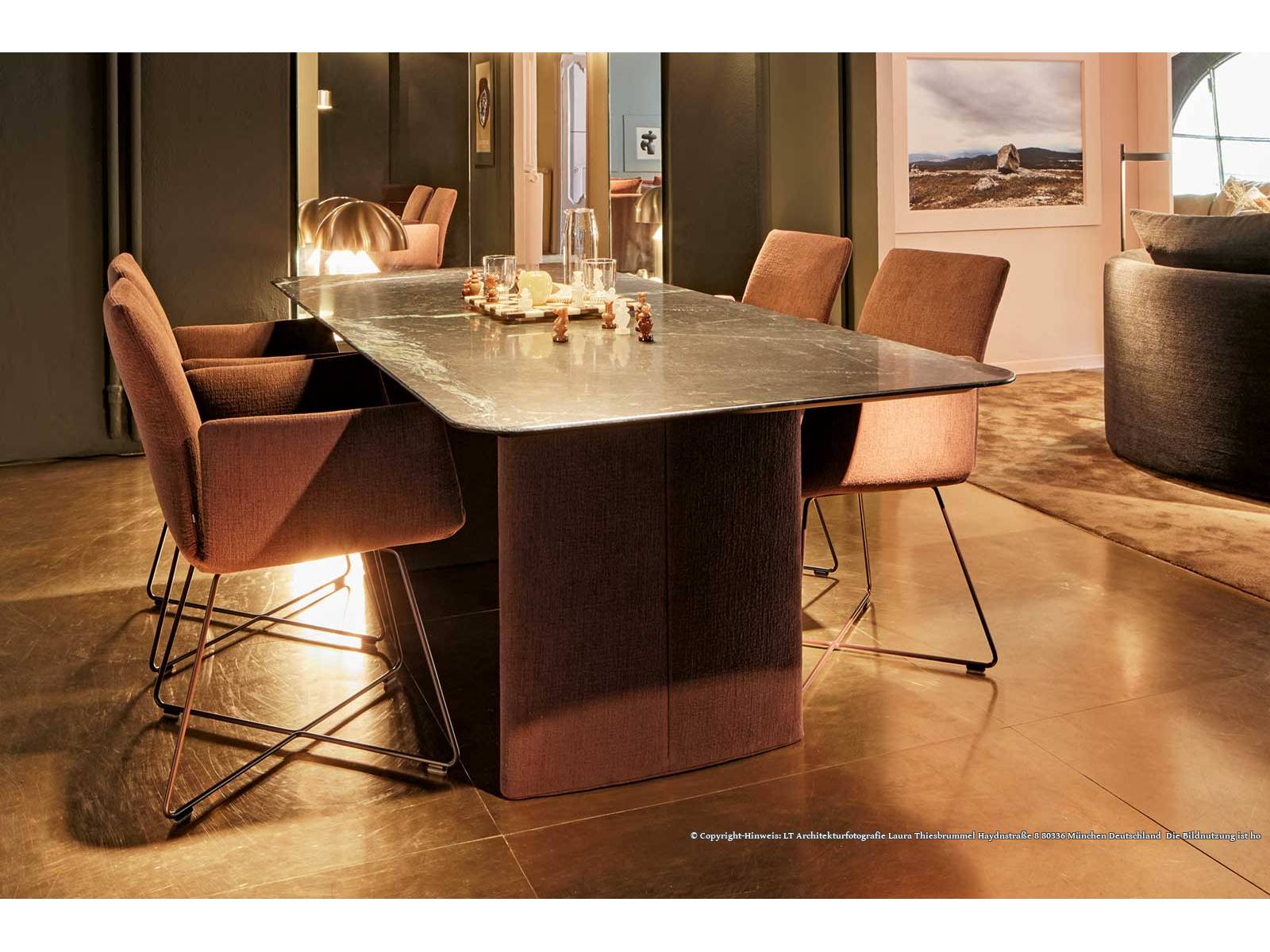 Die elliptisch gepolsterten Wangen des Esstisches «Ipa» bilden eine elegante Brücke zu den Stühlen im gleichen Bezugsstoff. So entsteht eine harmonische Wohnlichkeit, die auf dem raffinierten Konzept des Designteams Kräling-Lübke beruht. Foto Laura Thiesbrummel. COR.