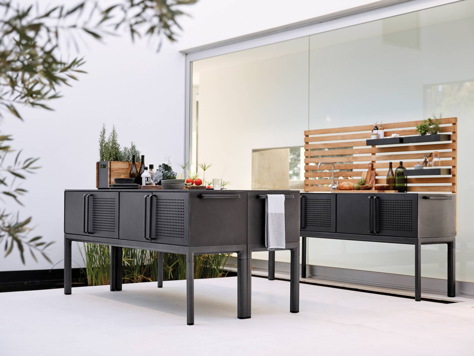 Das i-Tüpfelchen für die Sommersaison: Die modulbasierte Outdoor-Küche «Drop». Visuell so gestaltet, dass sie mit den Möbeln des Unternehmens, insbesondere den neuen Tischen der gleichnamigen Serie, harmoniert, wird sie aus Teakholz und Aluminium mit lavagrauer Pulverlackierung gefertigt. Tischplatte, Waschbecken und Mischbatterie sind aus Edelstahl. Cane-Line.