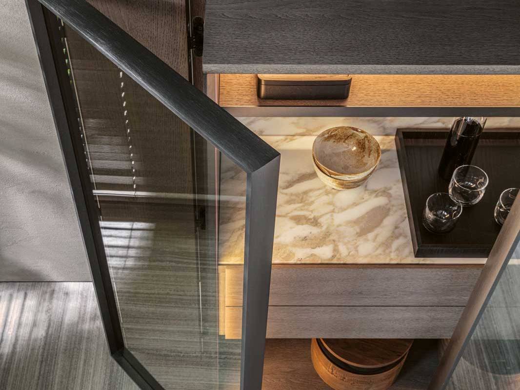 Materialien wie Eiche, Goldmarmor und Glas zeichnen das edle Aufbewahrungsmöbel «Hori-zons» aus. Eine LED-Beleuchtung im Inneren taucht das Möbel in einen warmen Ton. Die beiden Klapptüren lassen sich über zwei Seiten öffnen und ermöglichen so vollen Zugang zum Innenraum. Design: Dante Bonuccelli. Molteni.