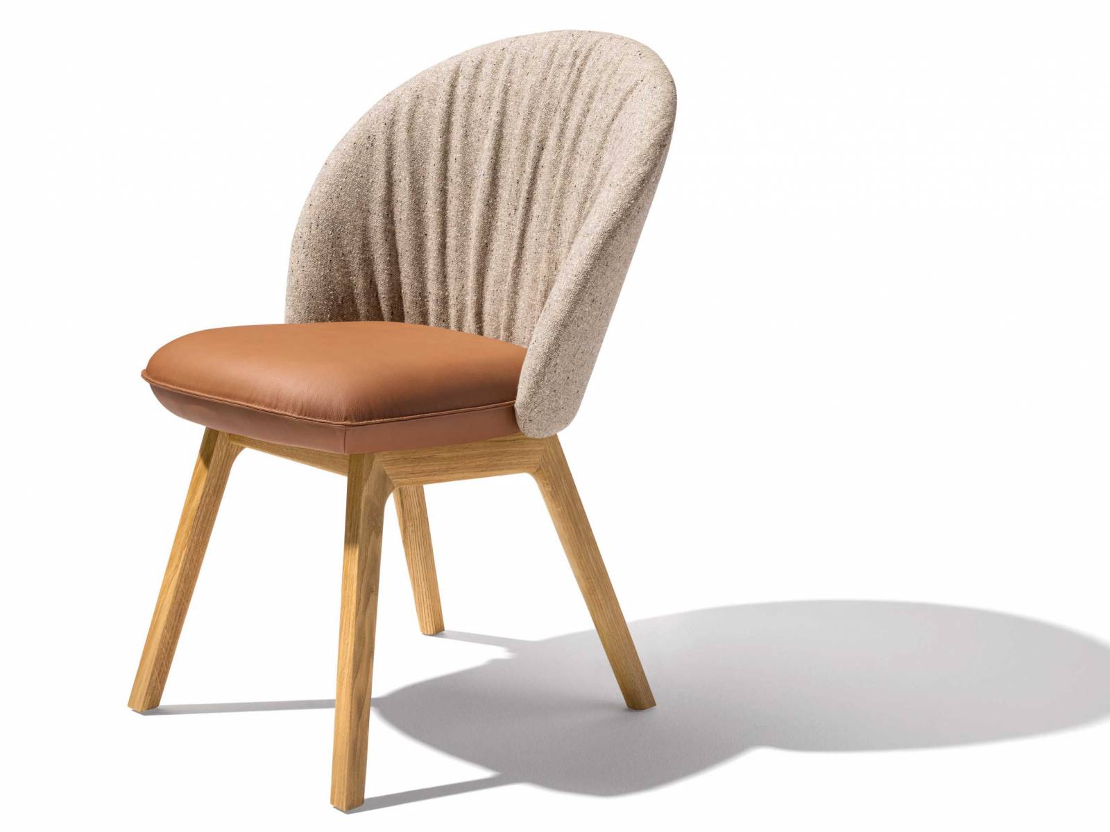 «Flor» ist ein Garant für Komfort und Wohnlichkeit. Ein schönes Detail bei diesem Stuhl ist der raffinierte Faltenwurf auf der Innenseite der Rückenlehne. Mit Textil bezogen, bildet diese einen attraktiven Kontrast zur Sitzfläche in Leder. TEAM 7.