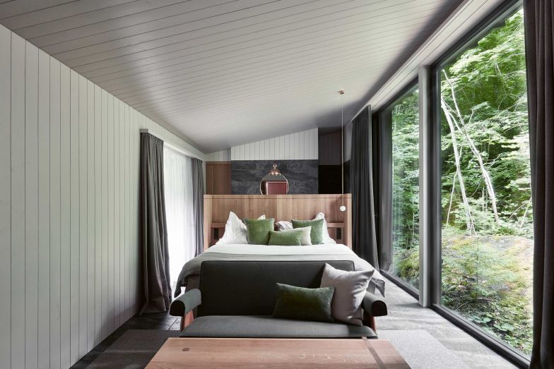 Das Mooshaus hat auf beiden Seiten grosszügige Fenster. Es ist eingebettet zwischen zwei mit Moos überwachsenen, grossen Felsen, die vom Steinsturz vor rund 15 000 Jahren dort gelandet sind. Hinter dem Bett liegt der offene Badbereich. Foto: Andrea Diglas Photography.