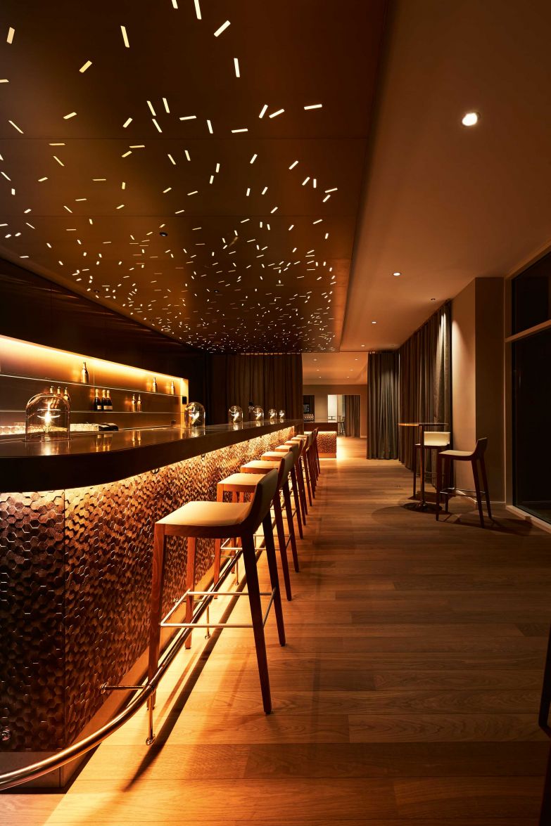 Goldene Sechsecke zieren die Front dieser Bar, für die eine individuell gelaserte Oberfläche mit 3D-Effekt entwickelt und mit Goldtönen patiniert wurde. Das mit dem preisgekrönten Verfahren Sublidot by Strasserthun veredelte Material wird jeweils individuell und nach Kundenbedürfnissen angefertigt. Foto: Andreas Hoernisch, Steigenberger Hotel Treudelberg. Strasserthun.