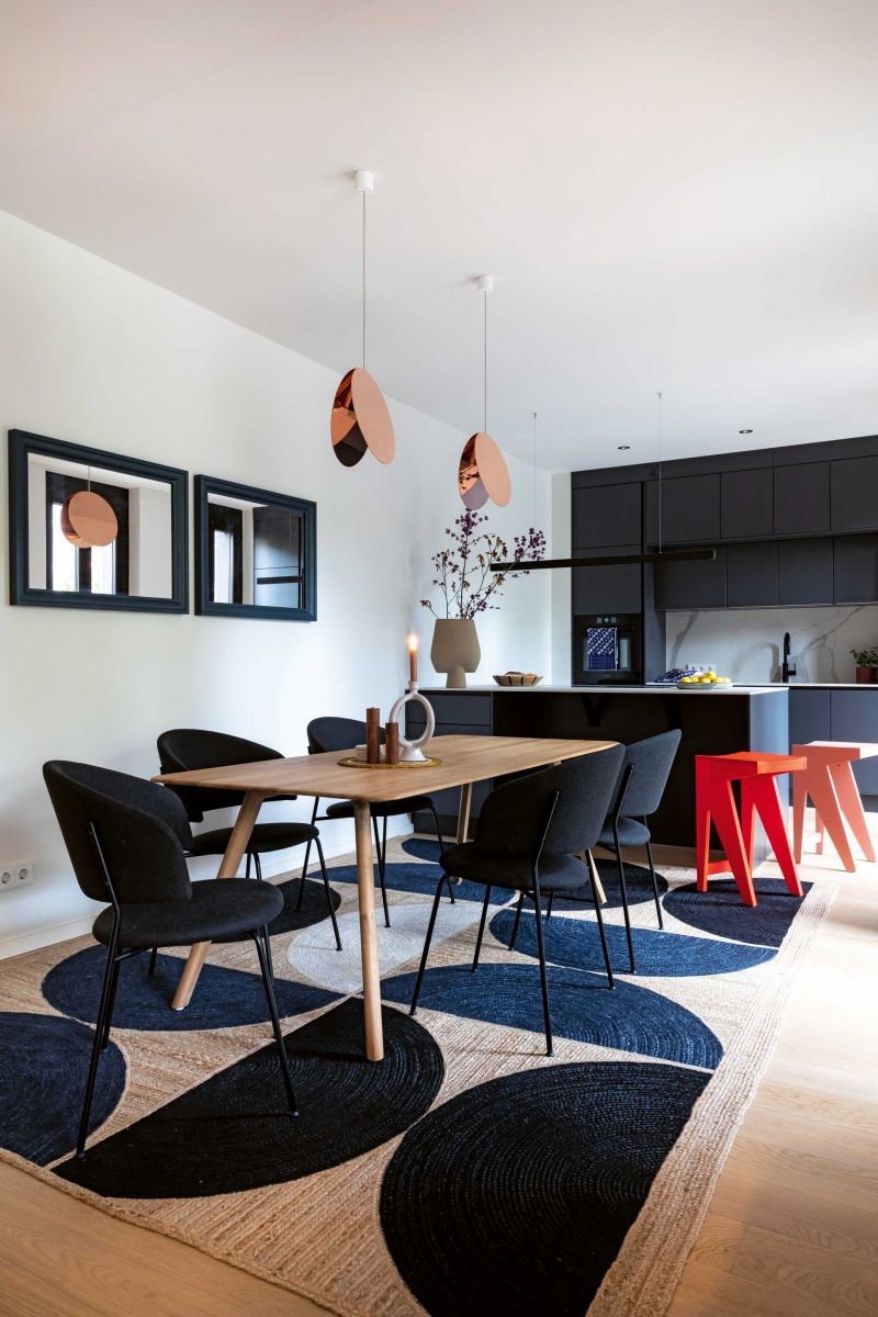 Hell-Dunkel-Kontraste und grafische Effekte mit einem Hauch von Neon: Die Küche ist edel und frech zugleich. Den Esstisch definiert ein grafischer Teppich von Elitis; die Hängeleuchte von e15 setzt weibliche Akzente. Designed und made in Berlin sind die Barhocker «Schulz» von Objekte unserer Tage.