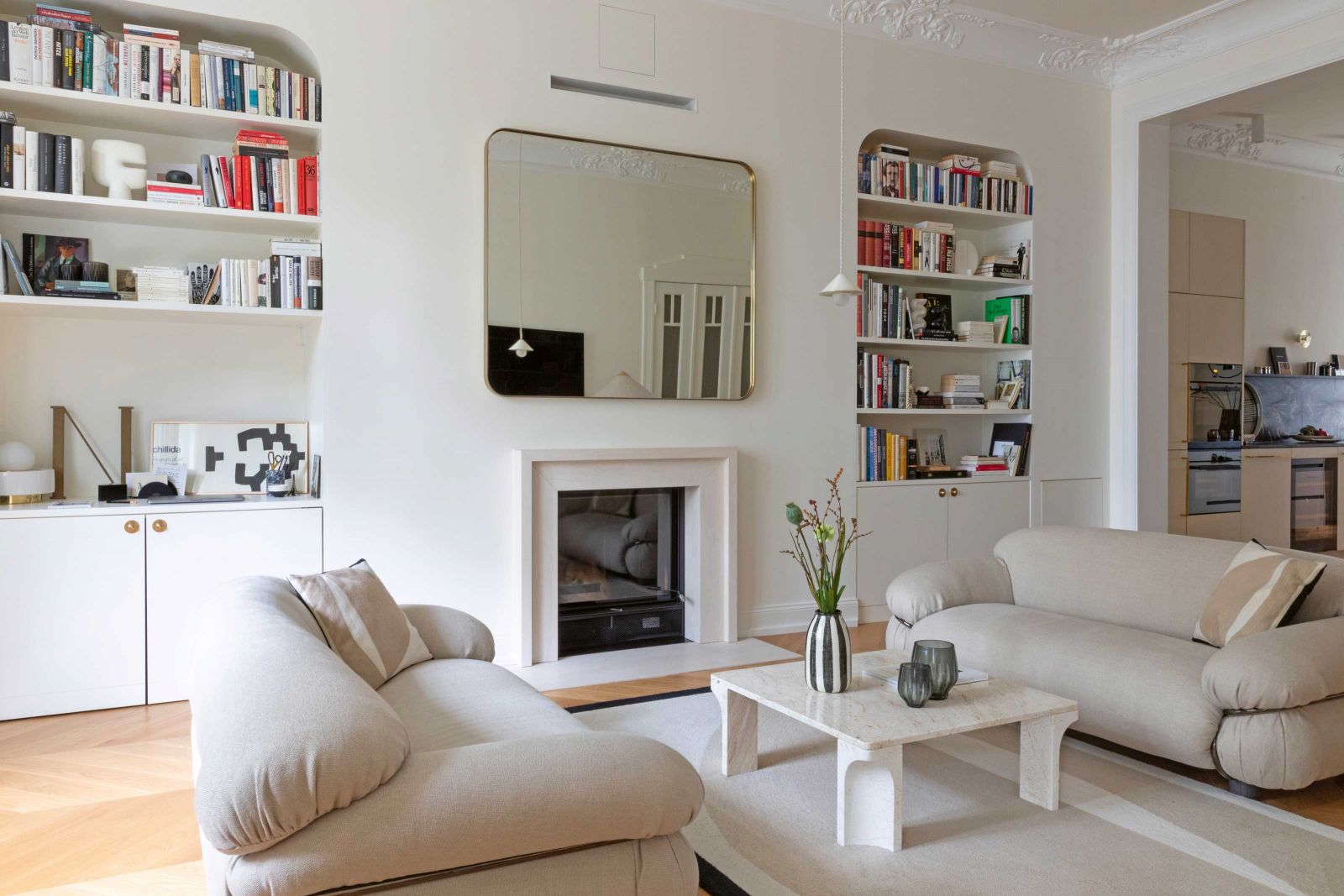 Die Sofas «Sesann» von Gianfranco Frattini dominieren den Wohnraum mit ihrem kühnen Volumen und ihrem eleganten, raffinierten Design. Die Bücherregale wurden bei der Renovierung eigens integriert. Spiegel, Teppich, Vasen: Maison Sarah Lavoine; Couchtisch, Stehleuchten: Gubi.