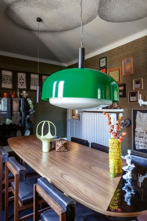 Im Esszimmer dominieren eher dunkle Farben und textile Materialen, wodurch der Raum intimer wirkt. Die Wandverkleidung aus Seide ist von Vescom. Der Tisch aus Palisanderholz wurde von einem Schreiner auf Mass gefertigt, die Stühle dazu stammen von Herman Miller und Simon Gavina. Für die Bilder an der Wand wurden verschiedene Ethno-Stoffe gerahmt. Vintage-Leuchte von Kartell.