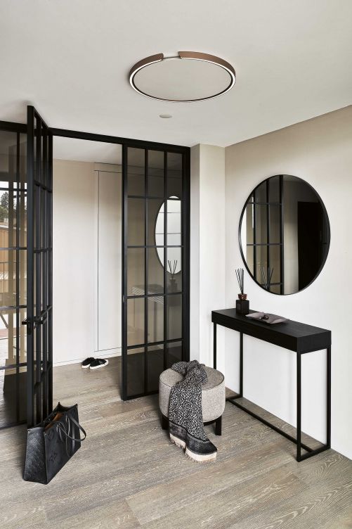 Der runde Spiegel, der schmale Konsolentisch «Mira» und Hocker «Rondo» im Entrée, beide Lambert, wirken filigran und leicht. Der massive Dielenboden aus Eichenholz strahlt optische Ruhe aus.