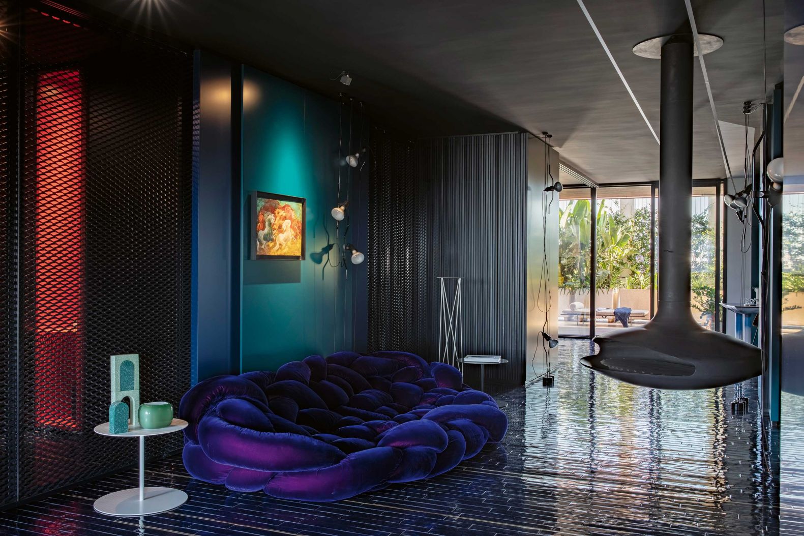 Dem offenen Küchenbereich schliesst sich der Wohnbereich an. Das Sofa «Boa blue», welches Fernando und Humberto Campana für Edra entwarfen, ist zusammen mit dem freihängenden Feuerplatz von Focus der Place to be. Der Beistelltisch «Gong» ist von Cappellini; die Leuchten sind von Flos und Davide Groppi.