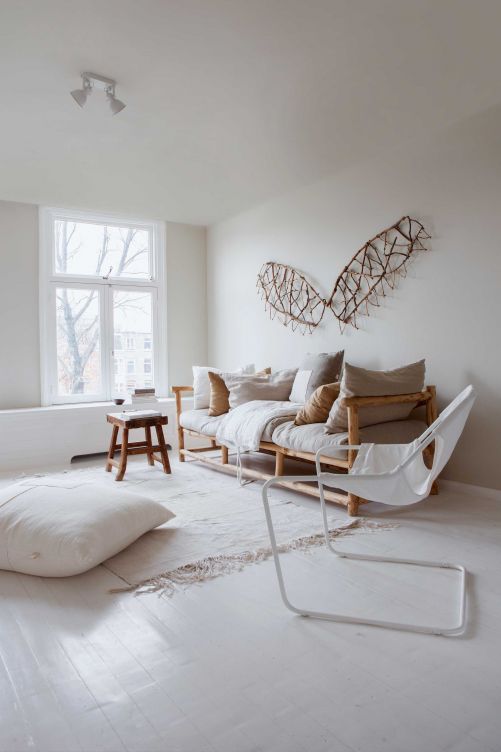 Die Couch ist aus Kastanienholz handgemacht. Das Kunstwerk an der Wand wurde aus Ästen von «Sandra Elewout» gefertigt. Die Leinenkissen von Fant Projects kombinierte Irene mit honigfarbenen Textilien von By Molle. Der «Paulistano Chair» ist ein Entwurf von Paulo Mendes da Rocha aus dem Jahr 1975. Teppich und Hocker: Atelier Sukha.