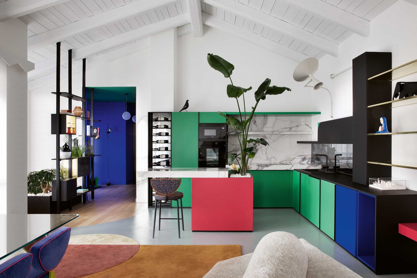 Die Küche erinnert an ein Gemälde von Piet Mondrian. Der schwarze Korpus wurde mit grünen, blauen und roten Farbflächen gefüllt und leuchtet vor der weissen Wand besonders intensiv. Eine witzige Idee ist die Strelizie, die direkt in die Kücheninsel gesetzt wurde und dem Raum Höhe und Natürlichkeit verleiht.