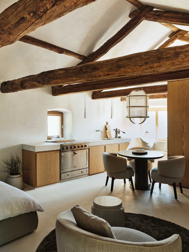 Blick vom Eingang in den Raum mit grosszügiger Küchenzeile, rundem Esstisch-Ensemble von Piet Boon sowie einer gemütlichen Sitzecke am Fenster vorne. Die Leuchte «Puro Lino» über dem Tisch ist eine Eigenkreation von Tanja Casparis.