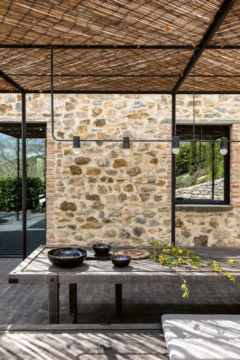 Vor dem Eingang zur Küche gibt es einen geschützten Essbereich. Tisch und Bänke entwarf Klaus Lichtenegger; die Leuchten über dem Tisch sind ein Entwurf des Büros Heinzelmann Ayadi aus München.