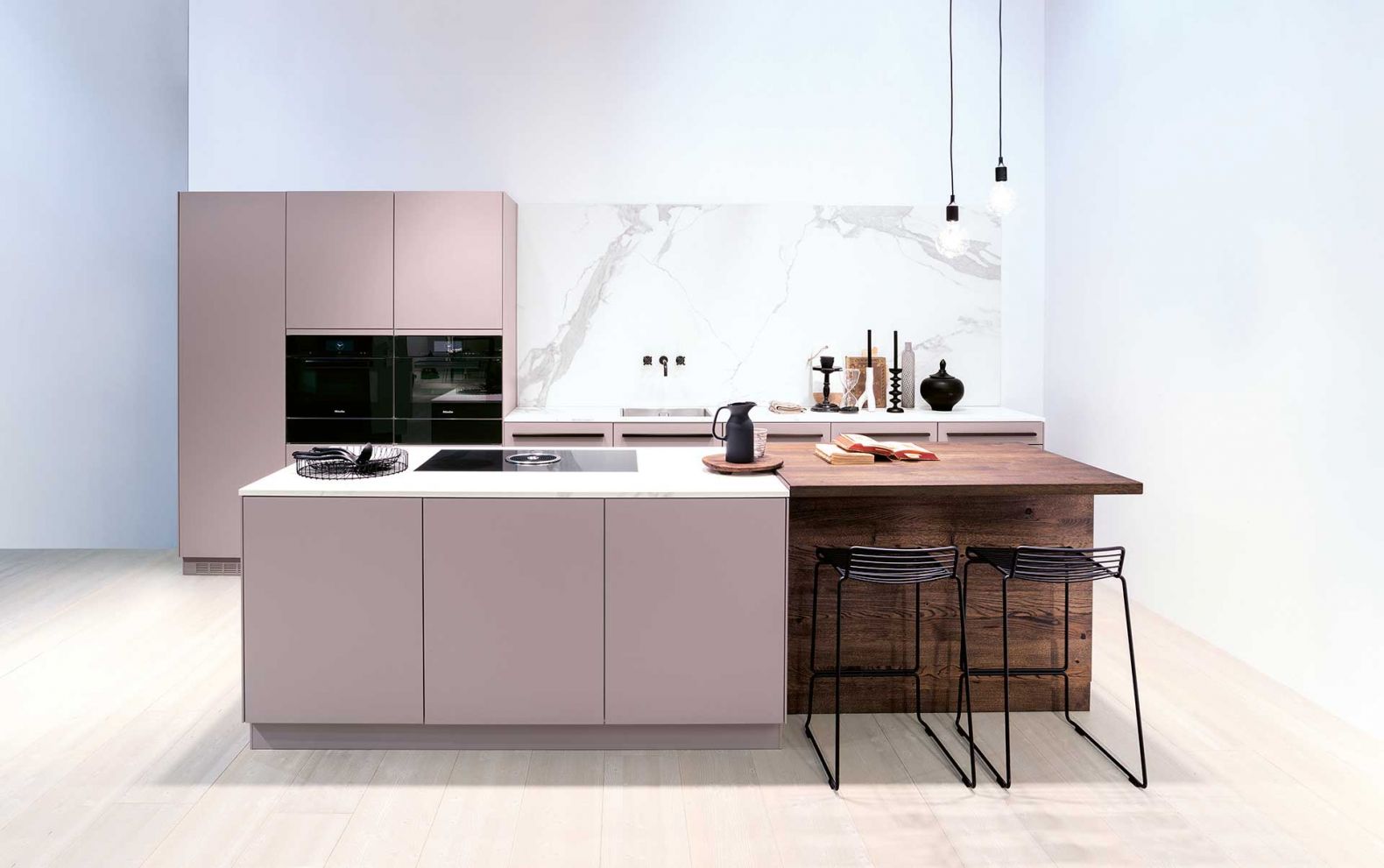Der Küche steht das Comeback von Rosatönen ganz besonders gut. Hier treffen sie auf klassisch-schönes Eichenholz und marmorierte Keramikoberflächen. Letztere machen sich als Arbeitsfläche gut, sorgen als Küchenrückwand mit schwarzer Wandarmatur aber auch für zusätzliche Eleganz. FORSTER.